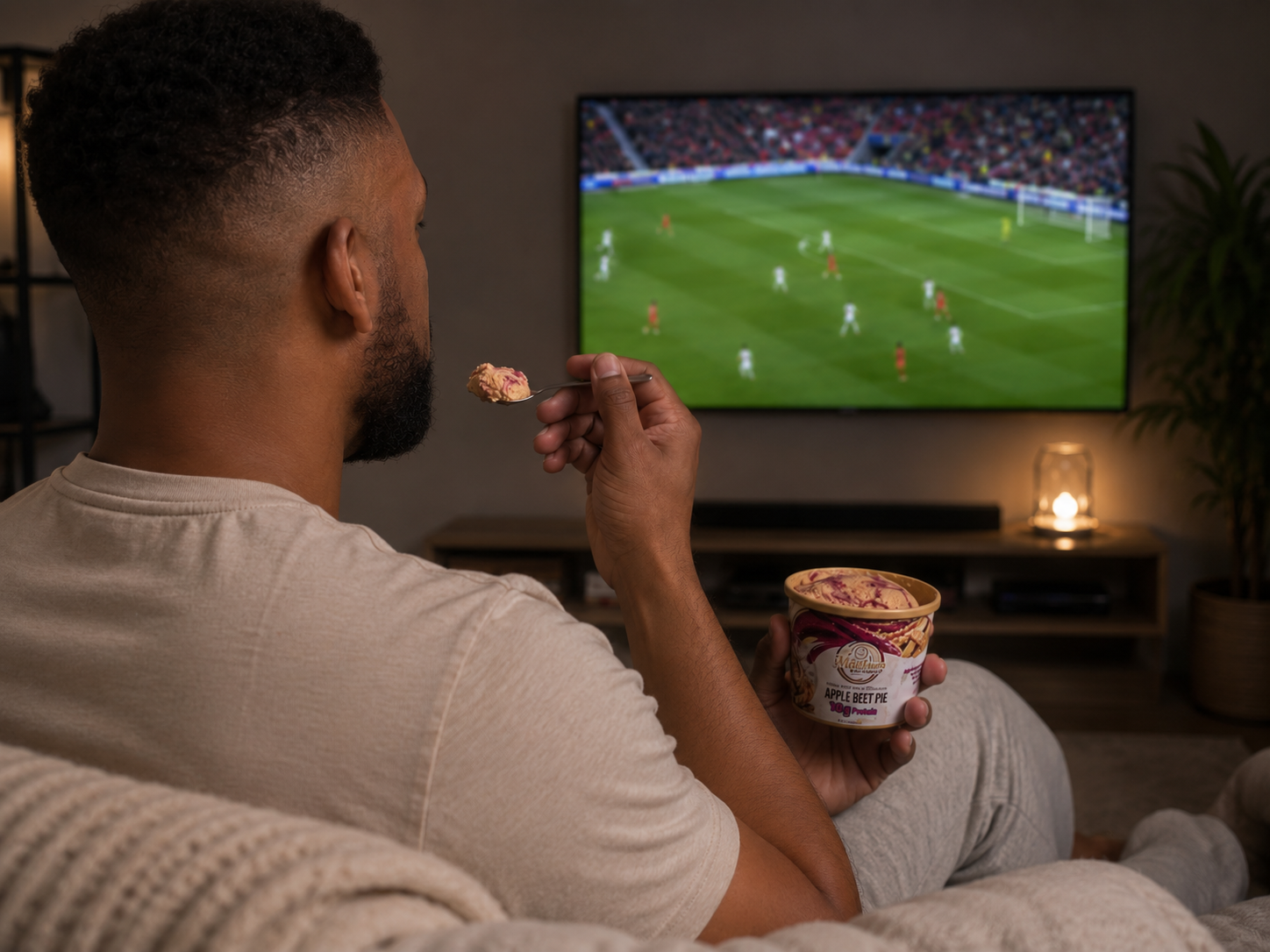 Man relaxing at home watching TV with a late-night comfort treat